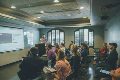a-group-of-people-in-a-room-with-a-projector-screen.jpg a group of people in a room with a projector screen
